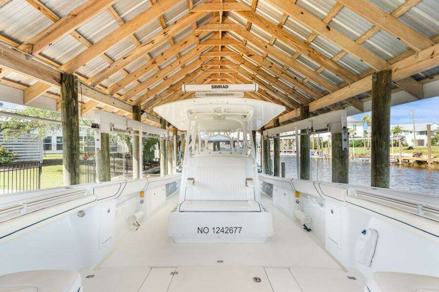 2015 Yellowfin 39 boat docked under wooden shelter by the water.