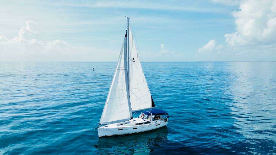 Sailing yacht Beneteau Oceanis 45, 2015 model, gliding on calm blue sea under clear sky.