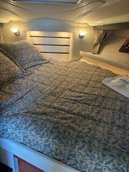 Cozy cabin interior of 2007 Monterey 350 Sport Yacht with patterned bedding and porthole window.