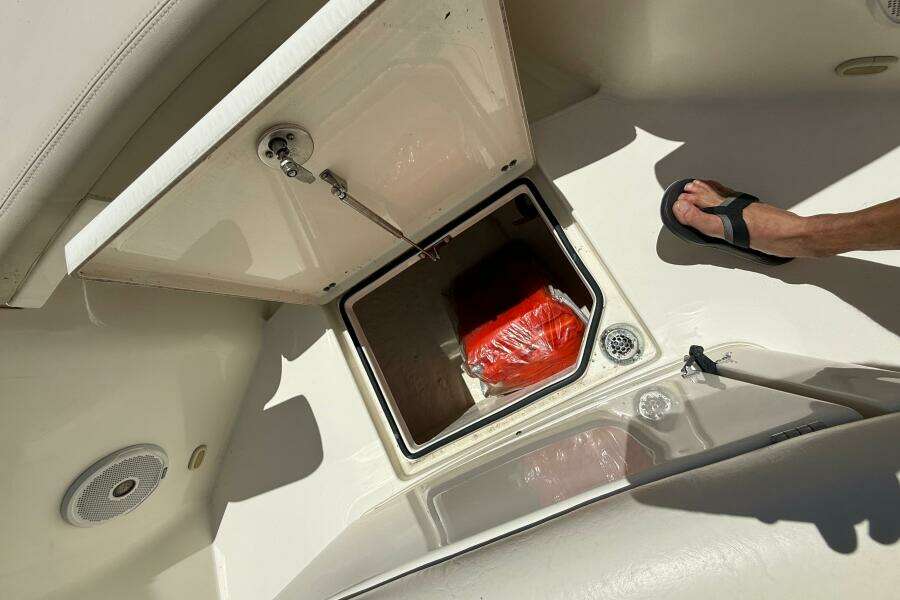 Open storage compartment on 2015 Cobia 296 Center Console boat, showing interior contents.