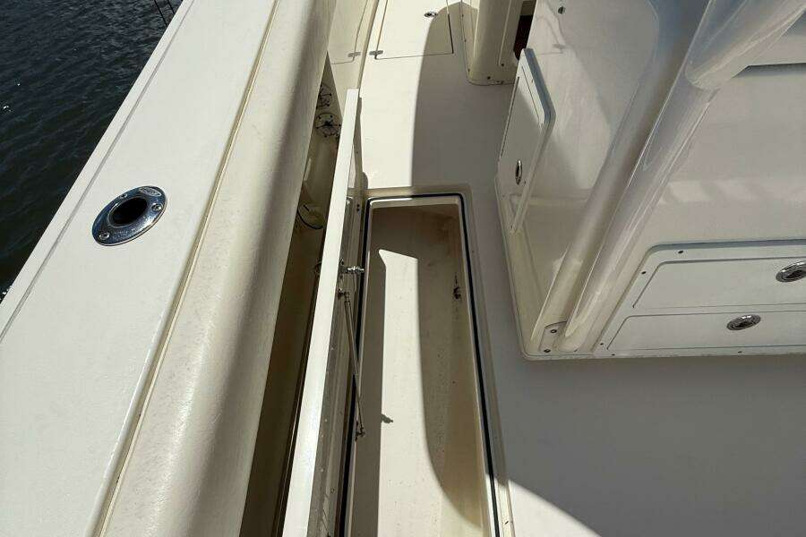 2015 Cobia 296 Center Console boat deck with storage compartment and rod holder.