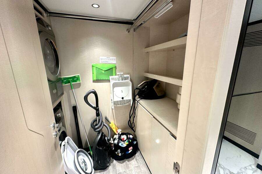 Laundry room in 2023 Majesty 120 yacht with washer, dryer, and cleaning supplies.