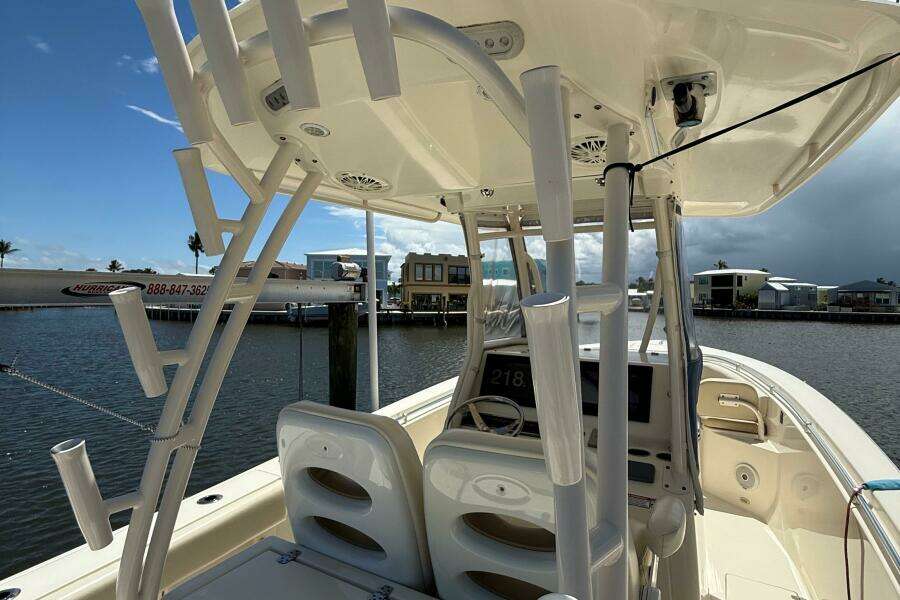 2015 Cobia 296 Center Console boat docked by waterfront homes under a cloudy sky.