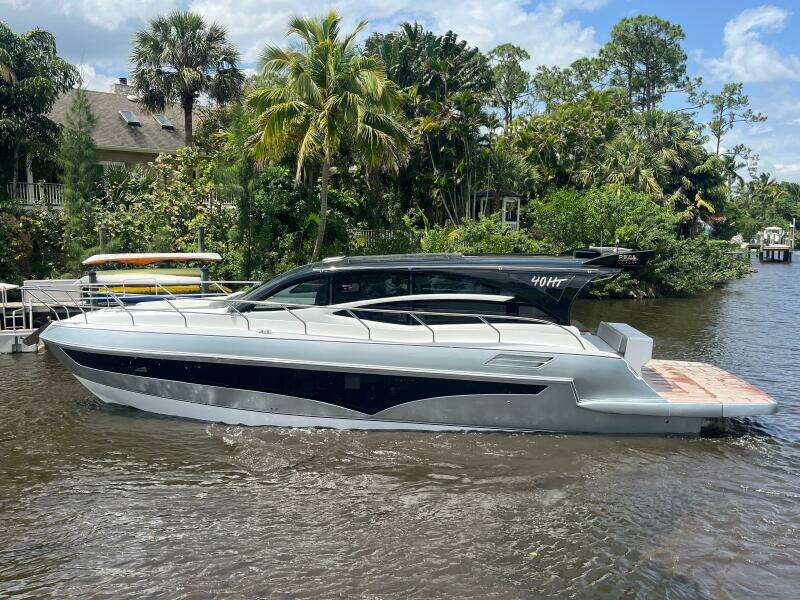 2025 Real 40 HT Luxury yacht on a river, surrounded by lush greenery and palm trees.
