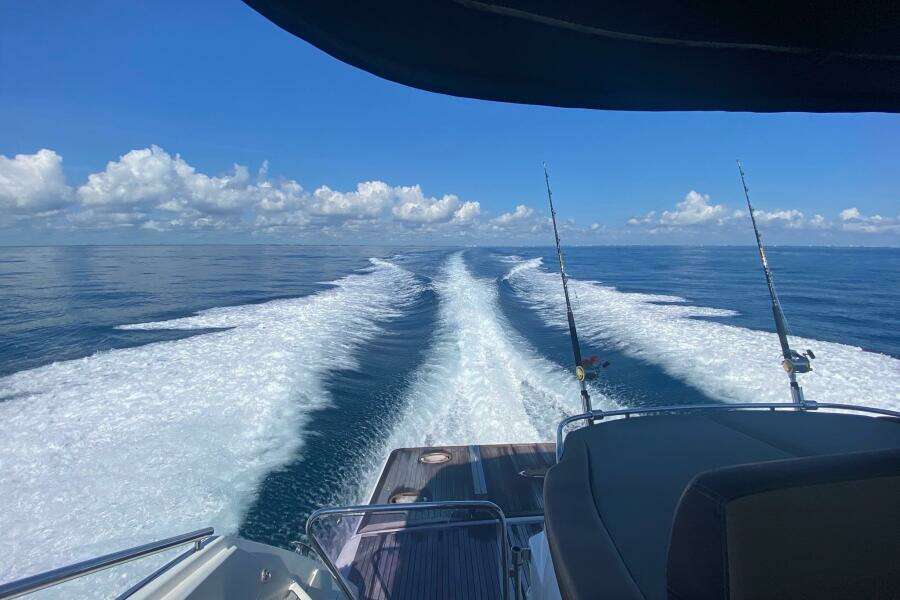 Beneteau Gran Turismo 44 yacht cruising, leaving a wake in the ocean, under a clear blue sky.