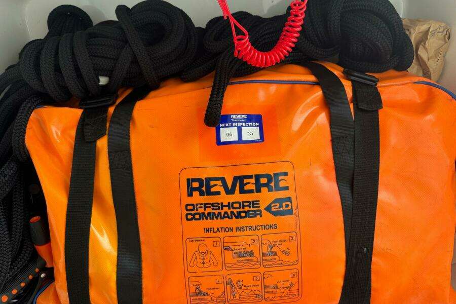 Orange Revere Offshore Commander 2.0 life raft bag with black straps and coiled ropes.