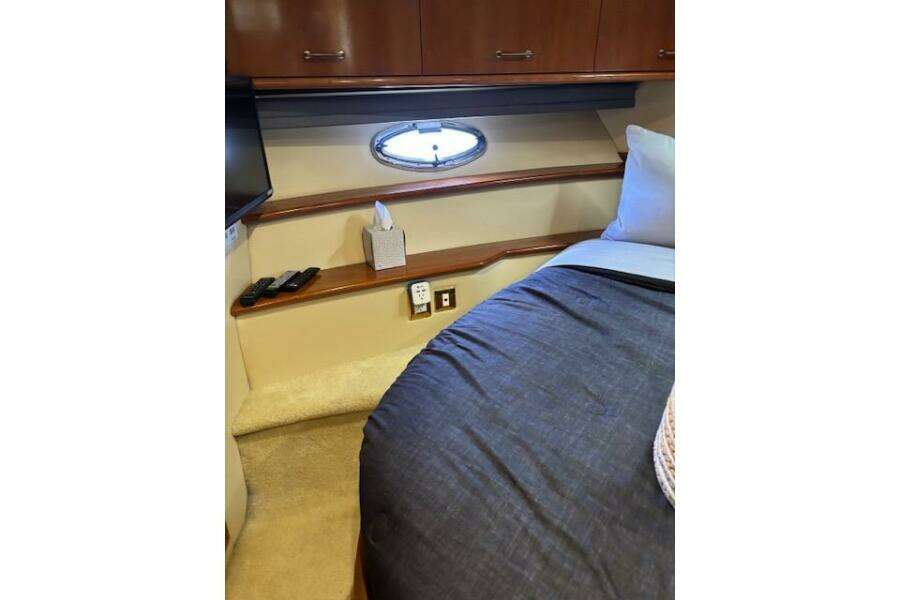 Interior of 2004 Carver 466 Motor Yacht bedroom with porthole, bed, and storage cabinets. Interior of 2004 Carver 466 Motor Yacht bedroom with porthole, bed, and storage cabinets.
