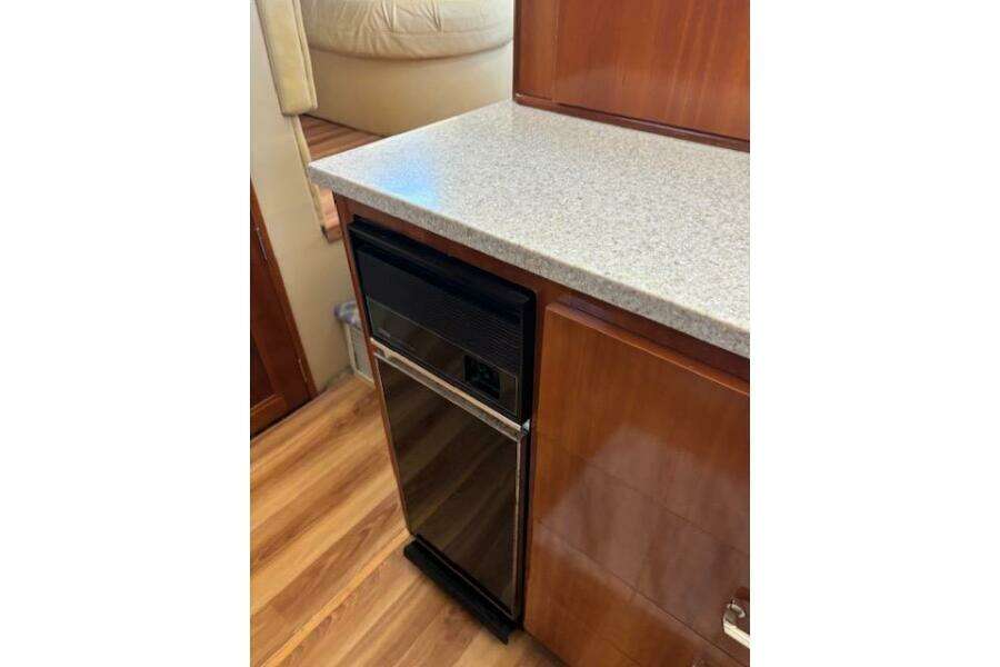 2004 Carver 466 Motor Yacht interior with compact fridge and wooden cabinetry. 2004 Carver 466 Motor Yacht interior with compact fridge and wooden cabinetry.