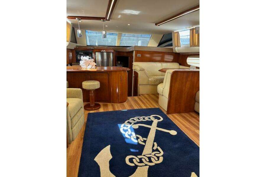 Luxurious interior of 2004 Carver 466 Motor Yacht with elegant wood finishes and anchor-themed rug. Luxurious interior of 2004 Carver 466 Motor Yacht with elegant wood finishes and anchor-themed rug.