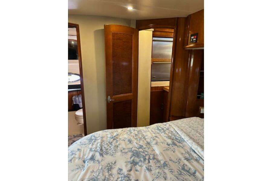 Interior of 2004 Carver 466 Motor Yacht bedroom with wooden cabinetry and floral bedding. Interior of 2004 Carver 466 Motor Yacht bedroom with wooden cabinetry and floral bedding.