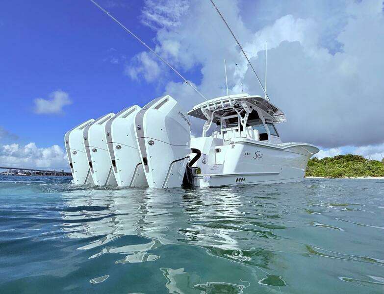 2024 Scout 400 LXF boat with multiple outboard engines on calm water.