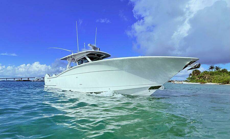 2024 Scout 400 LXF boat cruising in clear blue waters under a vibrant sky.