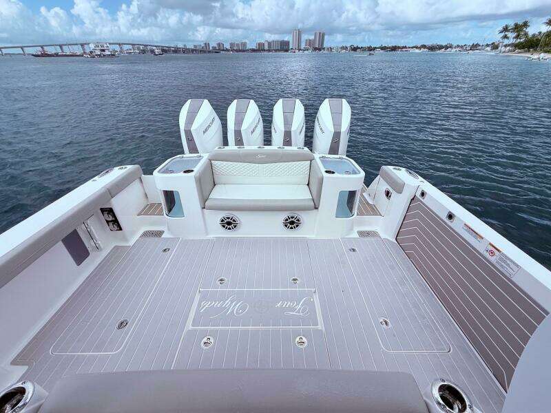 2024 Scout 400 LXF boat deck with four engines, overlooking a scenic waterfront.