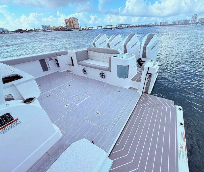 2024 Scout 400 LXF boat deck with seating and Mercury engines, overlooking a scenic waterfront.