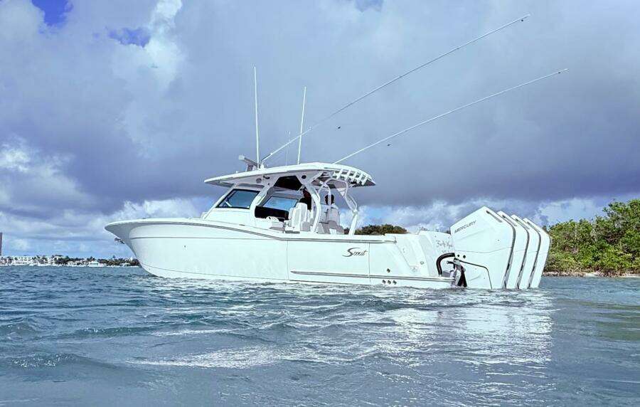 2024 Scout 400 LXF boat on water with triple Mercury engines, under cloudy sky.