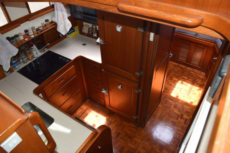 Interior Of 1997 Grand Banks Classic Yacht Kitchen With Wooden Cabinetry And Parquet Flooring.