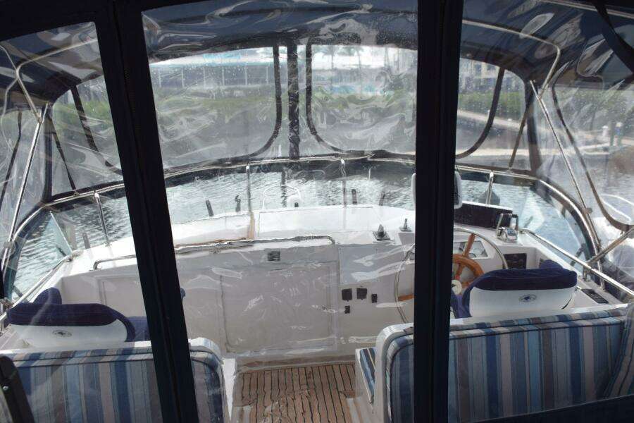 1997 Grand Banks Classic Yacht Cockpit With Striped Seating And Wooden Steering Wheel.