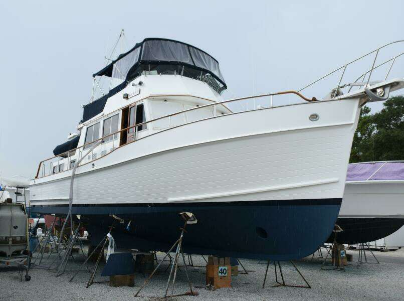1997 Grand Banks Classic Yacht On Stands, White Hull With Blue Bottom, In A Boatyard.