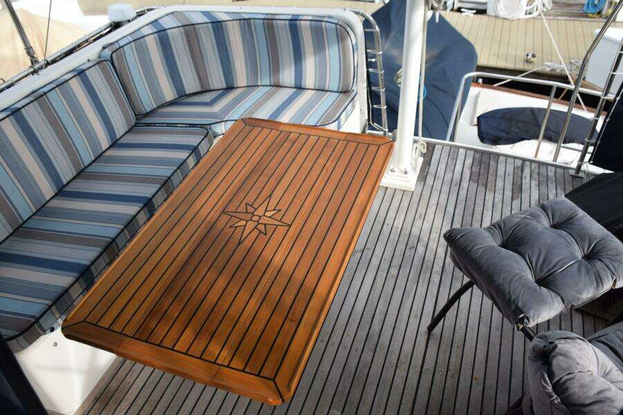 Luxurious 1997 Grand Banks Classic Yacht Deck With Striped Seating And Elegant Wooden Table.