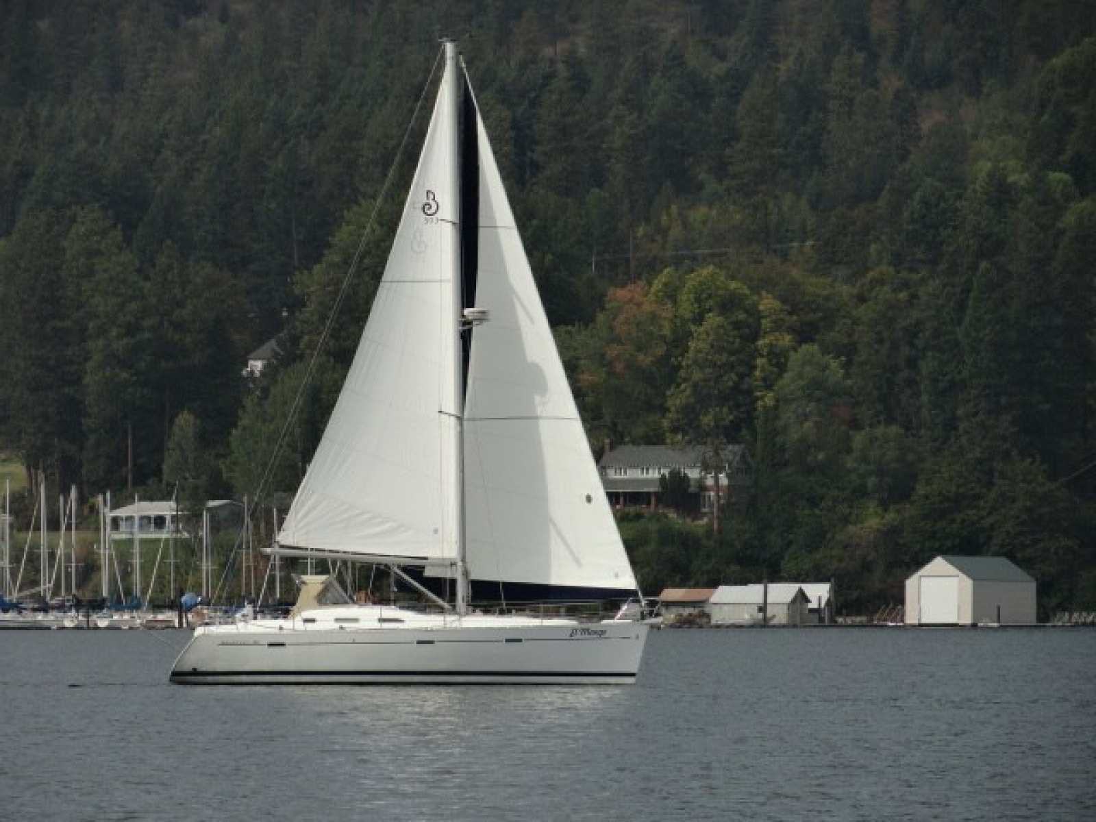 Sailing yacht Beneteau 393, 2007 model, gliding on a serene lake with forested backdrop
