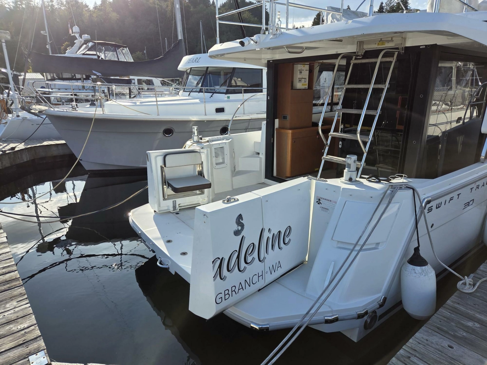 2020 Beneteau Swift Trawler 30 docked at marina, rear view with ladder and seating