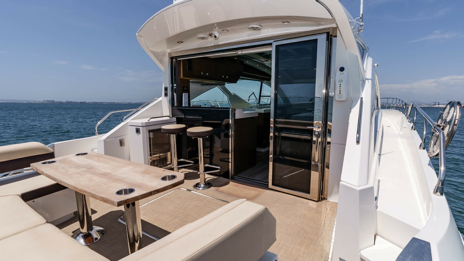 2017 Cruisers 60 Cantius, 'Rising Star' - Features a Luxurious Seating Area with a Sleek, Modern Table Perfect for Entertaining. The Seamless Transition to the Interior is Facilitated by Large Sliding Glass Doors, Opening up to a Stylish Bar with High Sto