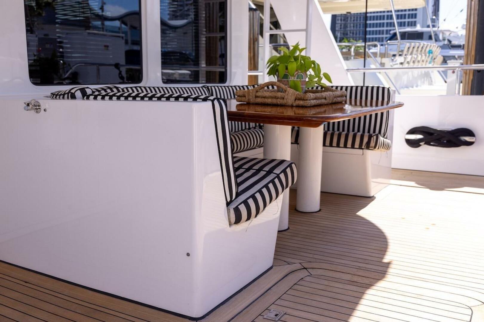 Luxury yacht deck with striped seating and wooden table, ABD