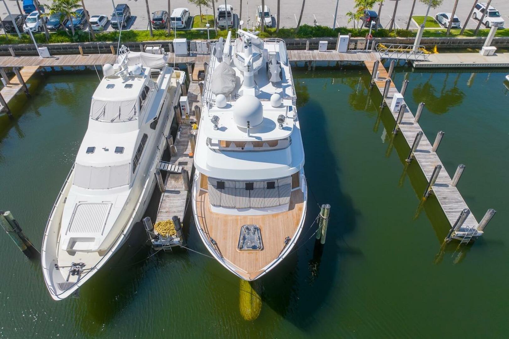 Two luxury yachts docked at a marina, featuring the 1996 ABD