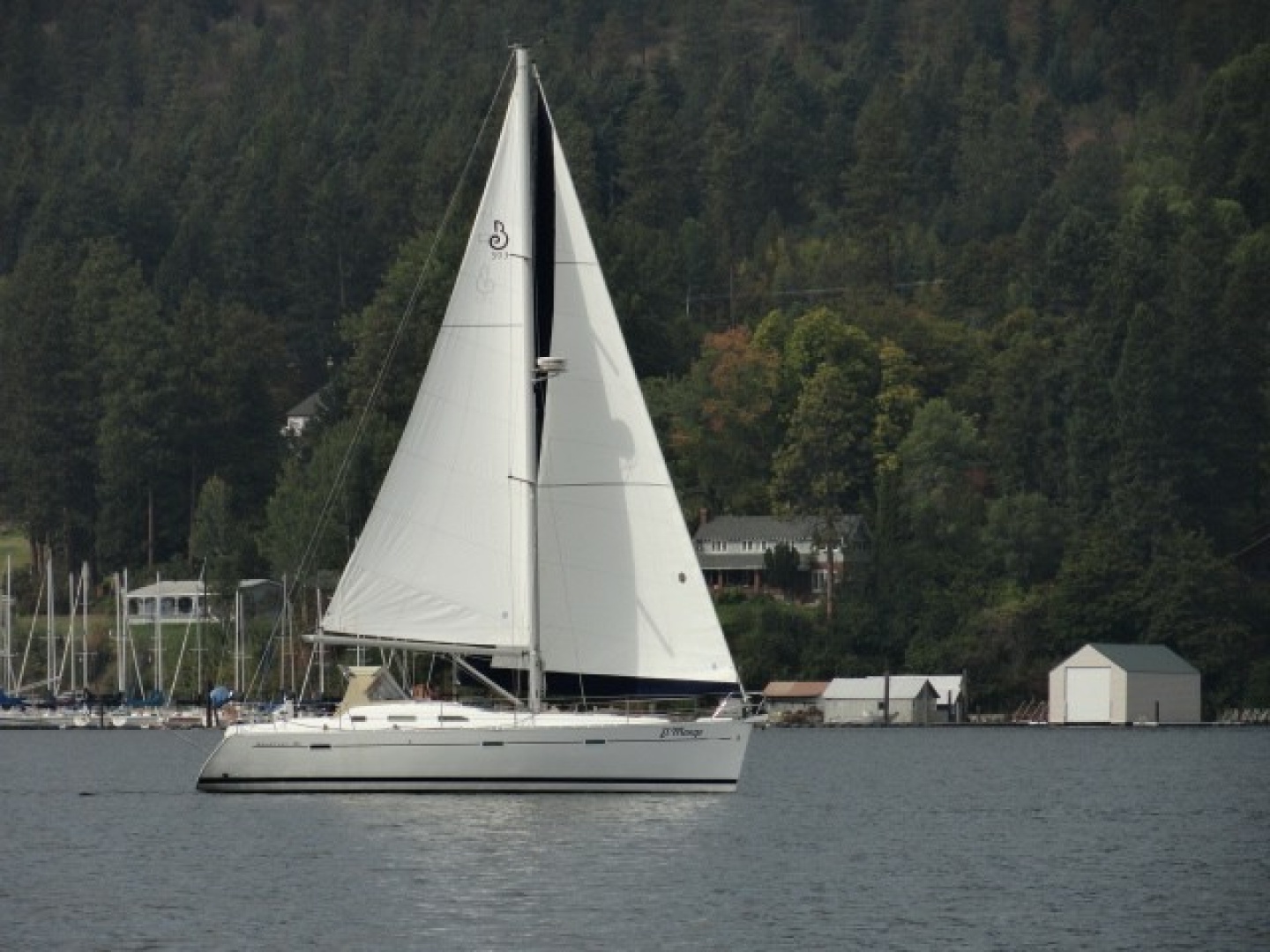 Sailing yacht Beneteau 393, 2007 model, gliding on a serene lake with forested backdrop