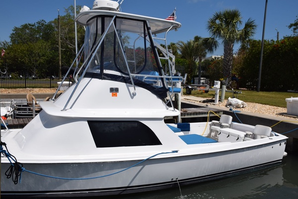 1976 Bertram Flybridge Cruiser Docked, Featuring Sleek Design And Spacious Deck Under Clear Blue Sky