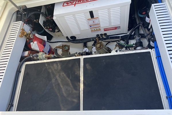 Engine compartment of 2023 Boston Whaler 350 Realm with generator and fire extinguisher.