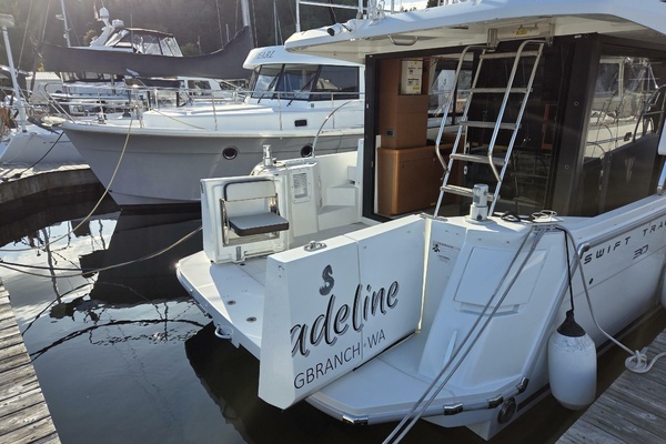 2020 Beneteau Swift Trawler 30 docked at marina, rear view with ladder and seating