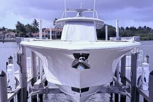 2024 Scout 400 LXF boat docked, front view with water and cloudy sky background.