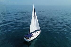 2015 Beneteau Oceanis 45 sailing on calm blue ocean waters.