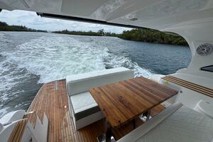 Luxurious 2025 Real 40 HT yacht interior with wooden table, cruising on a scenic waterway.